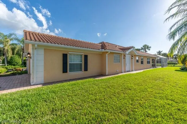 Rear view of property with a lanai and a yard