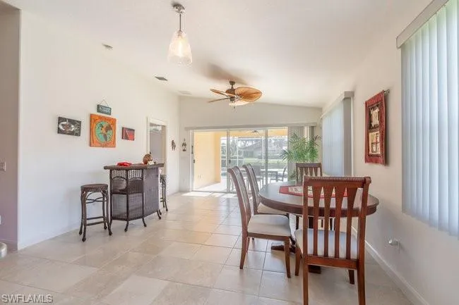 Tiled dining room featuring lofted ceiling and ceiling fan