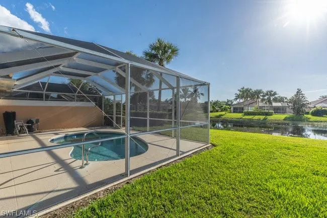 View of pool with a lawn, a lanai, a water view, and a patio area