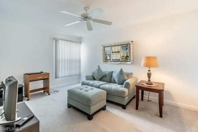 Carpeted living room featuring ceiling fan