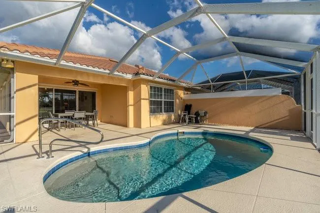 View of swimming pool with a patio, ceiling fan, and glass enclosure