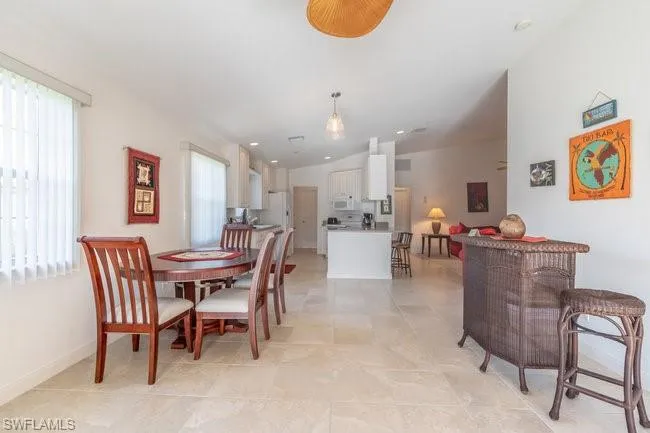 Dining area featuring plenty of natural light, light tile patterned floors, and vaulted ceiling