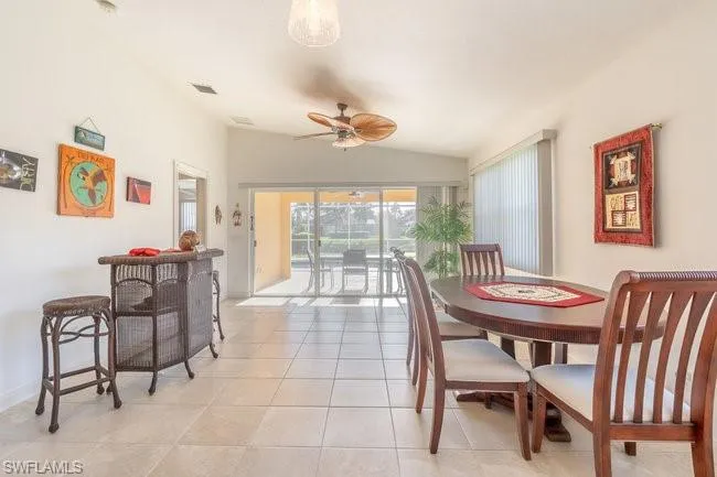 Dining room with lofted ceiling, light tile patterned floors, and ceiling fan