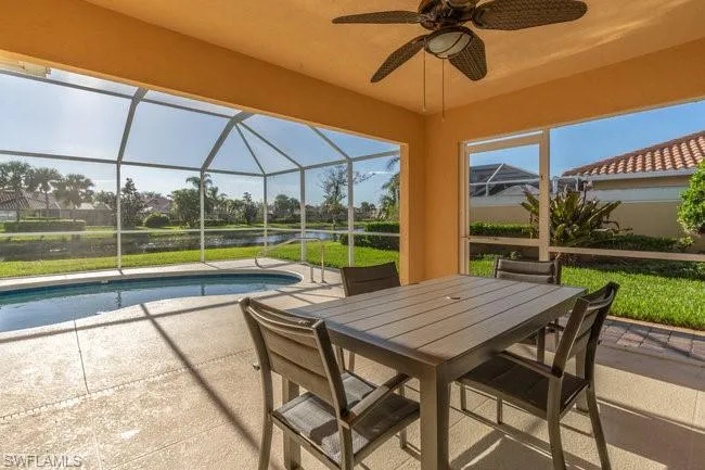 View of pool with a lanai, a water view, ceiling fan, and a patio area