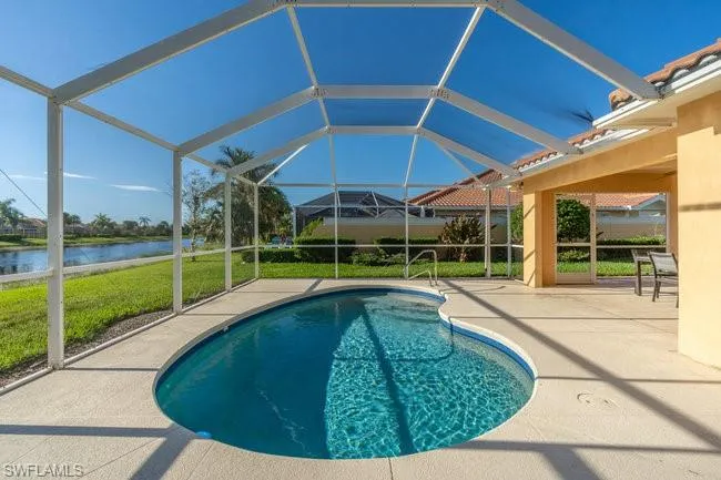 View of swimming pool featuring a patio area, a water view, a lawn, and a lanai