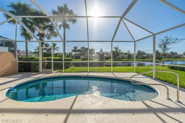 View of swimming pool featuring a patio, glass enclosure, and a water view