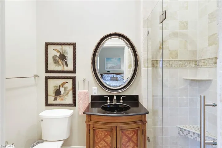 Bathroom featuring a shower with shower door, vanity, and toilet