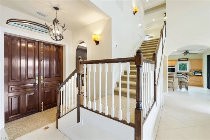 Foyer entrance featuring light tile patterned floors and ceiling fan with notable chandelier