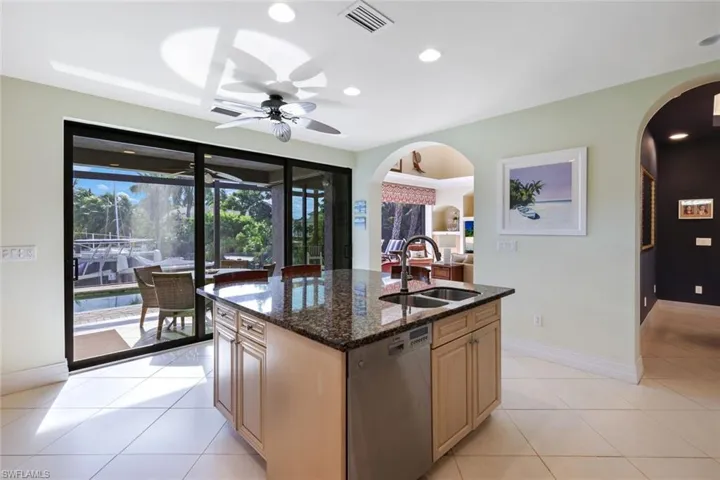 Kitchen featuring light tile patterned flooring, dishwasher, an island with sink, ceiling fan, and sink