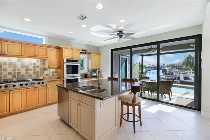 Kitchen with sink, a wealth of natural light, stainless steel appliances, and a kitchen island with sink