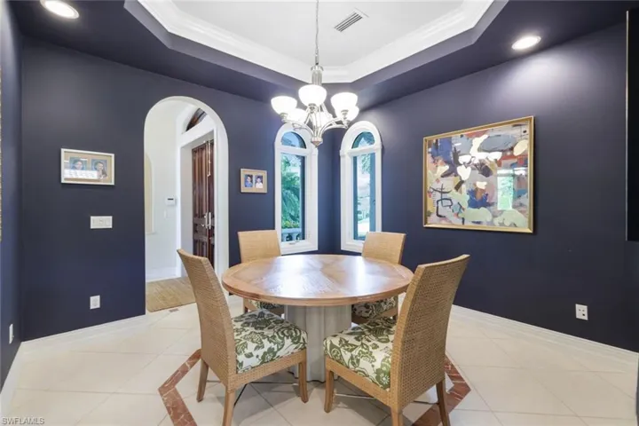 Dining space with light tile patterned flooring, an inviting chandelier, and a raised ceiling