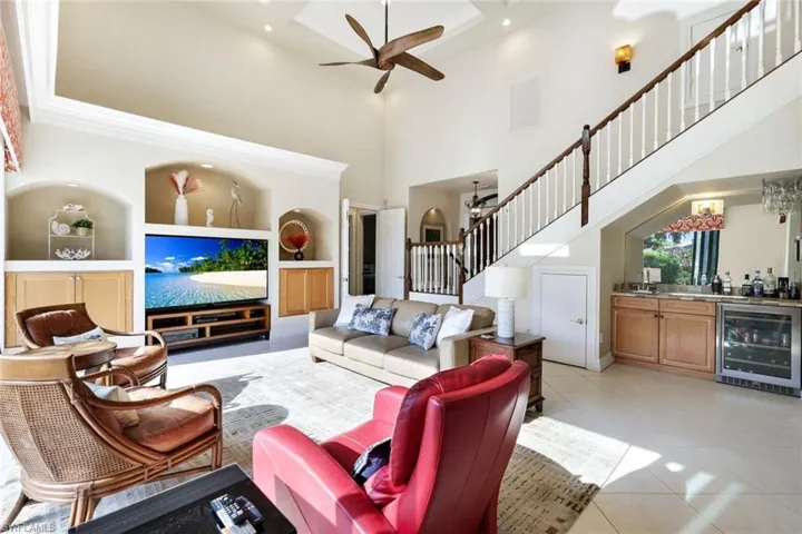 Tiled living room with ceiling fan, a high ceiling, and beverage cooler