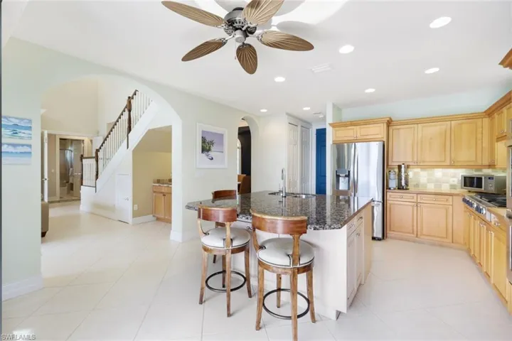 Kitchen with stainless steel appliances, decorative backsplash, ceiling fan, sink, and dark stone counters