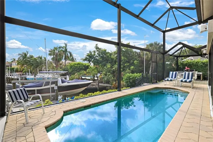 View of swimming pool featuring glass enclosure and a patio