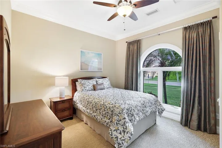 Bedroom featuring ceiling fan, crown molding, and light carpet