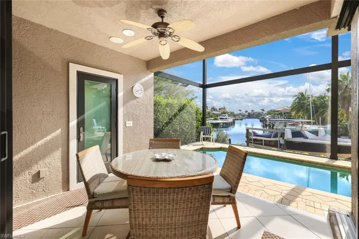 Sunroom with ceiling fan and a water view