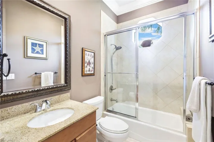 Full bathroom with combined bath / shower with glass door, toilet, ornamental molding, and vanity