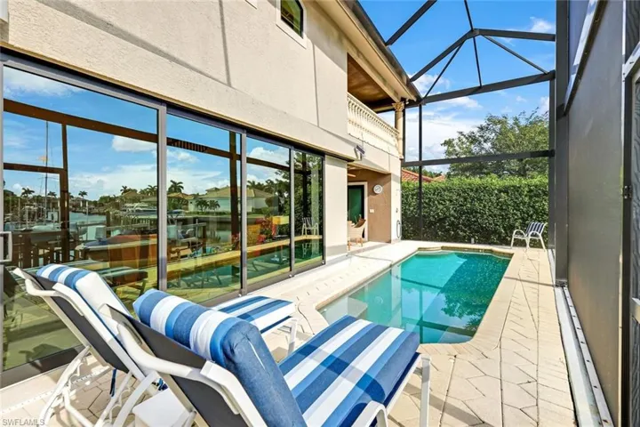 View of pool featuring glass enclosure and a patio area