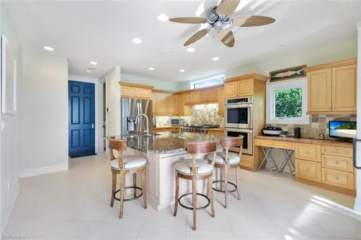 Kitchen with decorative backsplash, a kitchen island with sink, stainless steel appliances, and a breakfast bar
