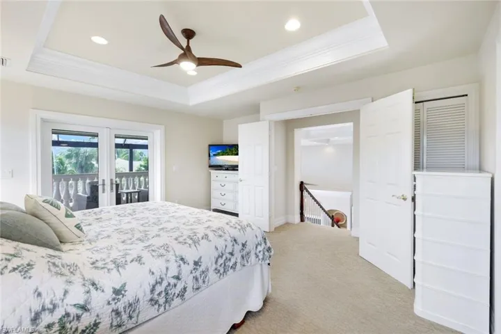 Bedroom with access to exterior, a tray ceiling, french doors, and carpet