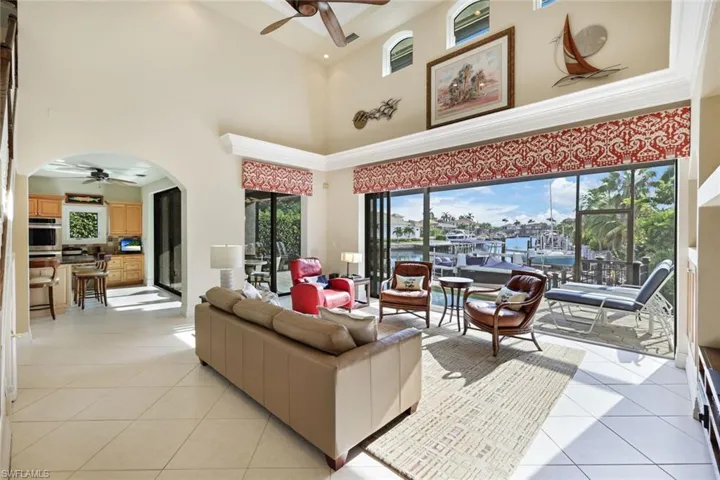 Tiled living room with ceiling fan, a towering ceiling, and a wealth of natural light
