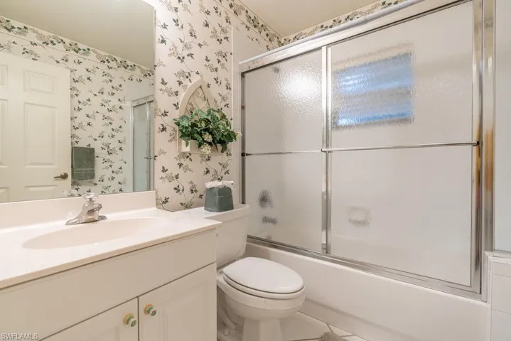 Full bathroom featuring vanity, tile patterned flooring, toilet, and combined bath / shower with glass door