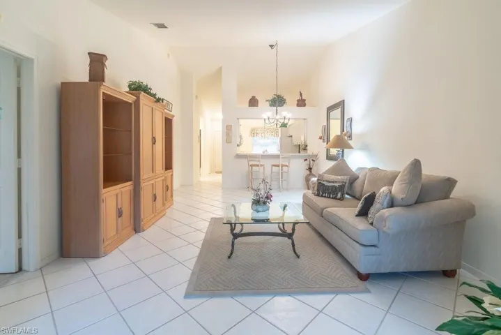Living room with light tile patterned floors, a notable chandelier, and vaulted ceiling