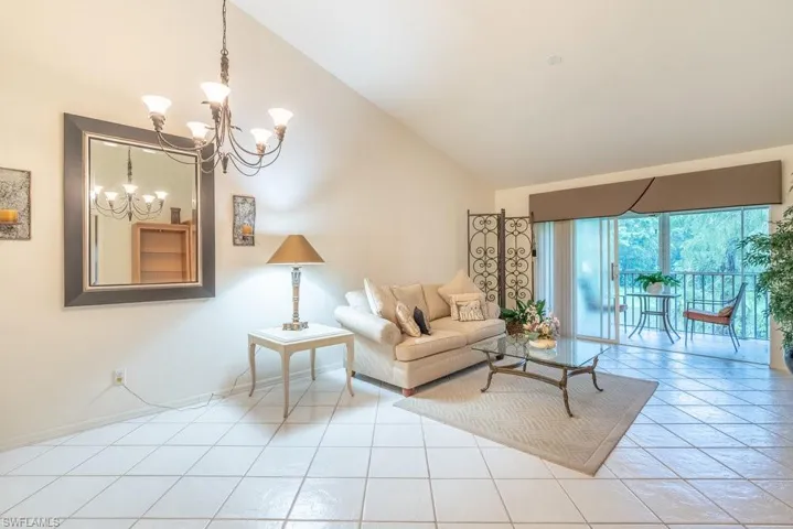 Living room featuring high vaulted ceiling, a notable chandelier, and light tile patterned floors