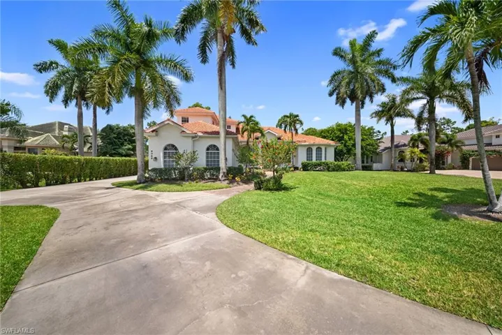 Mediterranean-style residence featuring a terracotta tile roof, arched windows, and a light-toned stucco exterior