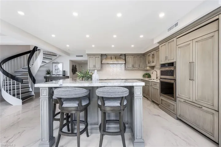 Kitchen showing built in refrigerator and wide spiral staircase