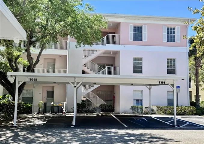 View of apartment building / complex featuring stairs and covered parking