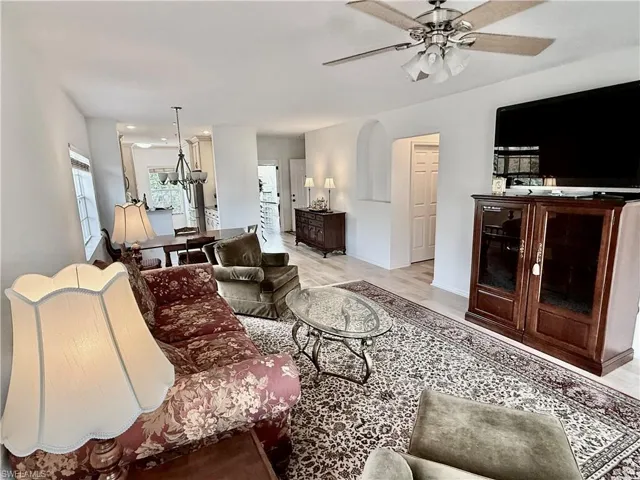 Living area with a chandelier, light wood-type flooring, and a ceiling fan