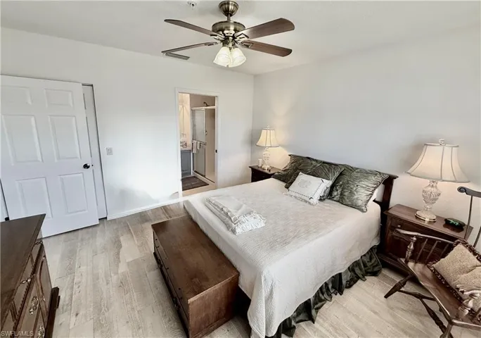 Bedroom featuring light wood finished floors, connected bathroom, and a ceiling fan