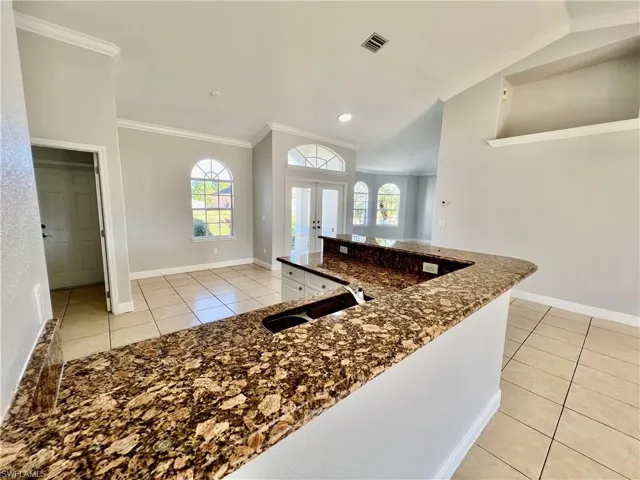 Kitchen with white cabinetry, white appliances, GRANITE TOPS, crown molding and a breakfast bar and pantry.