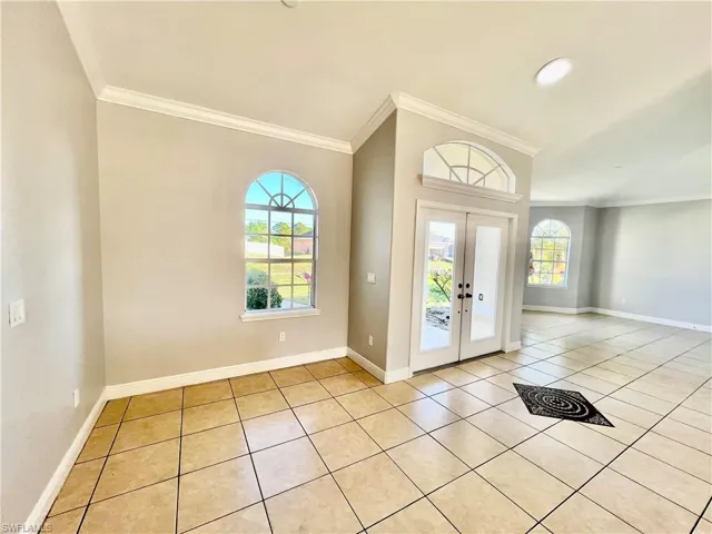 Entrance foyer featuring crown molding, light tile patterned floors, and French doors