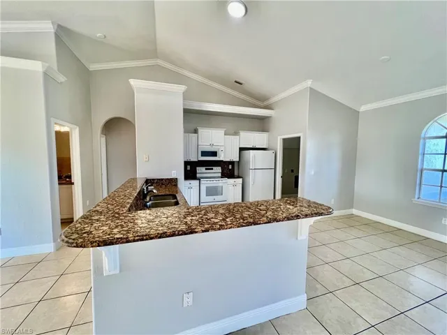 Kitchen with white cabinetry, white appliances, GRANITE TOPS and a breakfast bar and pantry.
