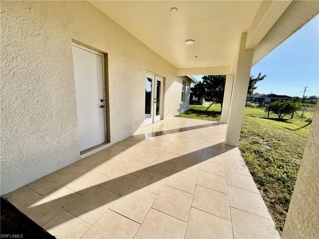 View of covered patio with tile floors overlooking the backyard.