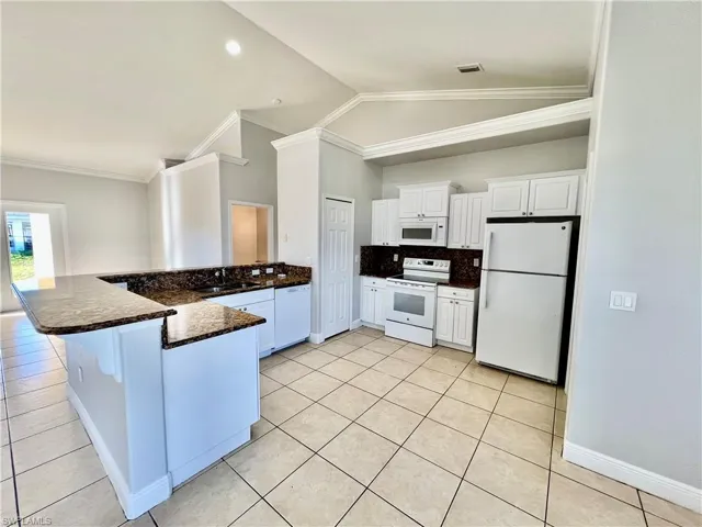 Kitchen with white cabinetry, white appliances, GRANITE TOPS and a breakfast bar and pantry.