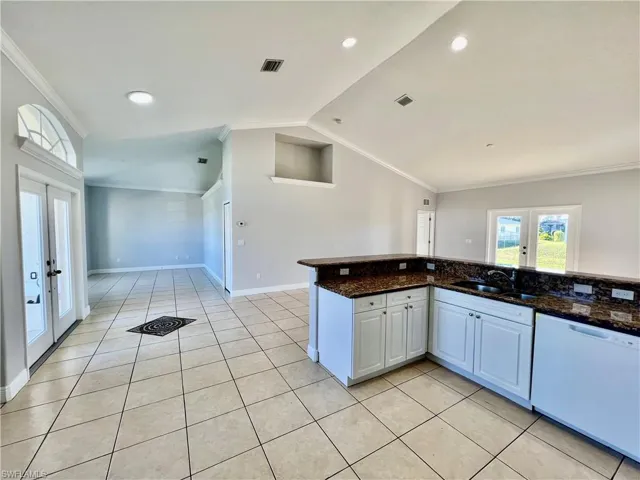 Kitchen open to family room and formal living room with plant shelves and crown molding.