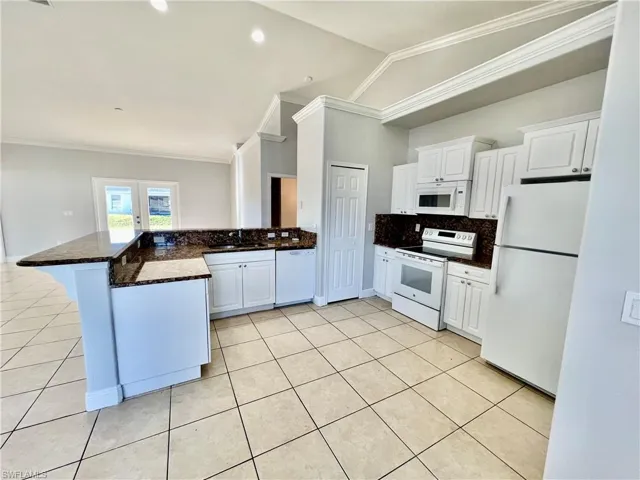 Kitchen with white cabinetry, white appliances, GRANITE TOPS and a breakfast bar and pantry.
