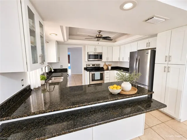 Kitchen featuring granite-style countertops, white cabinetry with display glass, stainless steel appliances, and recessed lighting