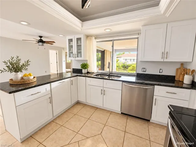 White shaker cabinetry with dark stone countertops, stainless steel appliances, and a tile flooring