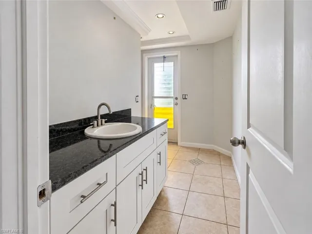 White cabinetry with brushed nickel hardware, black countertop, undermount sink, and a single-handle faucet