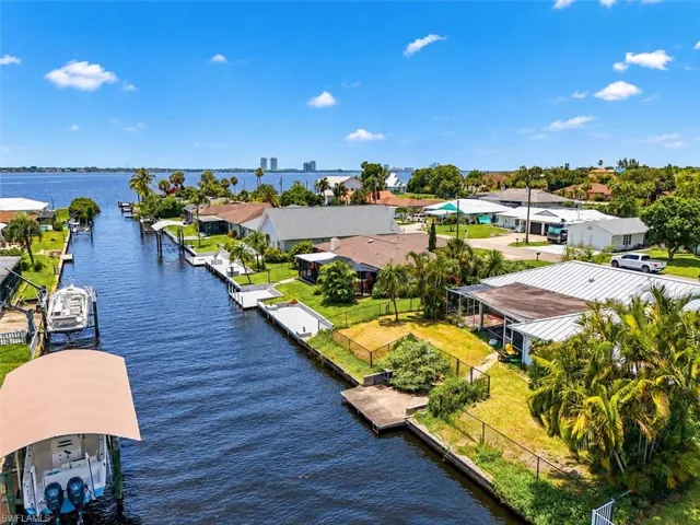 Waterfront property with canal access, featuring a concrete seawall and mature landscaping