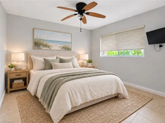 Light gray wall finish, ceiling fan with wood-finish blades, window with horizontal blinds, wall-mounted television, and tile flooring