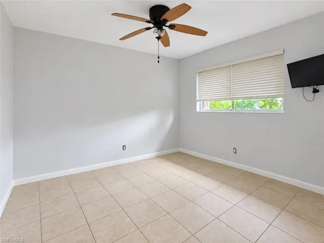 Recessed window with horizontal blinds, overhead ceiling fan with light fixture, and tile flooring