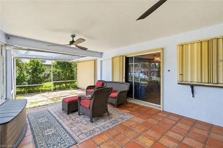 Screened outdoor patio featuring a tile floor, dual ceiling fans, and sliding glass doors