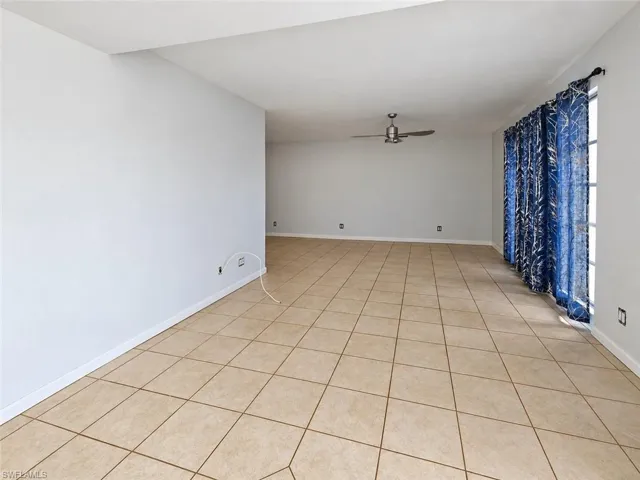Spacious room featuring tile flooring, neutral wall tones, and a ceiling fan