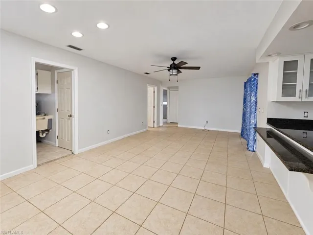 Recessed ceiling lighting, tiled flooring, ceiling fan, white cabinetry, dark countertop