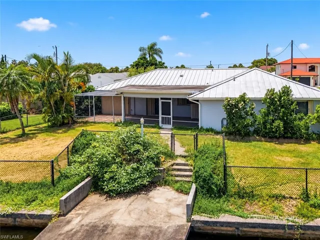 Waterfront property featuring a metal roof, screened porch, chain link fencing, and concrete seawall